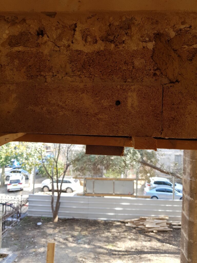פתח קשתי מעוטר בגילוף פרחוני מוביל למסדרון