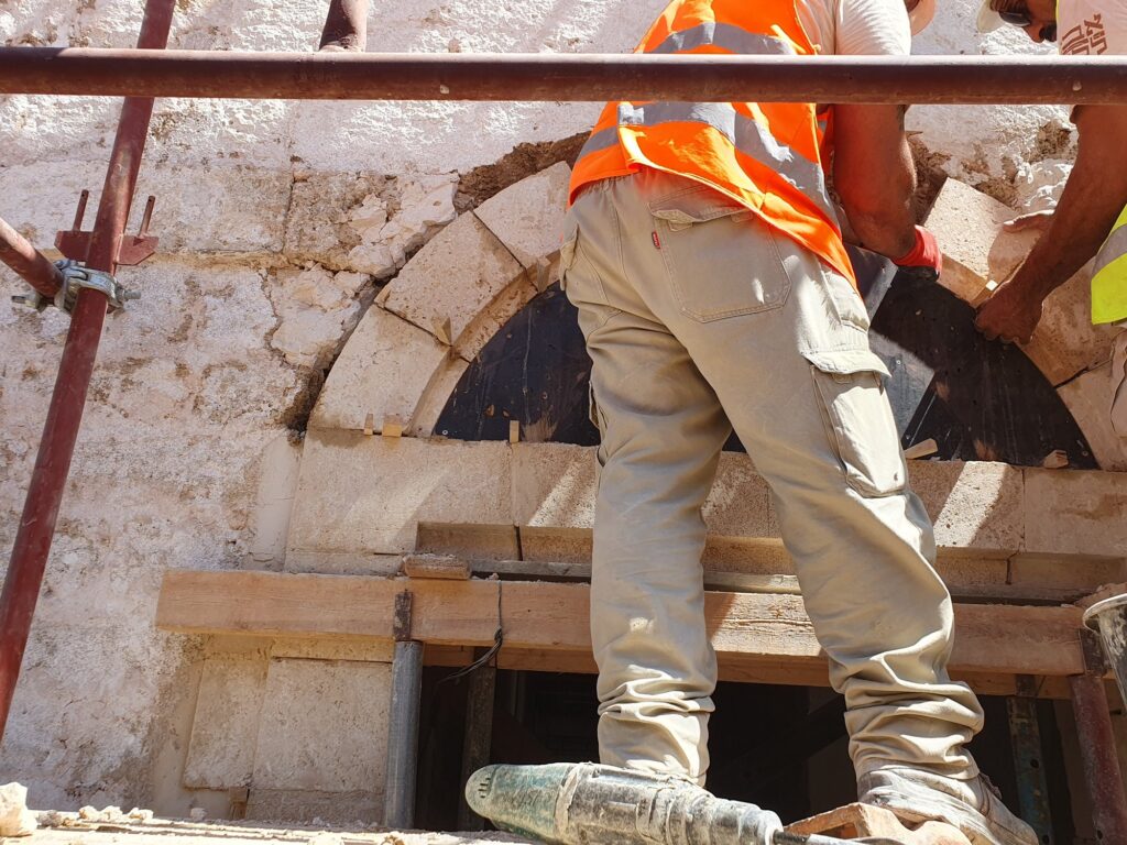 צוות פועלים מרים ומתקין אבן קשת גדולה