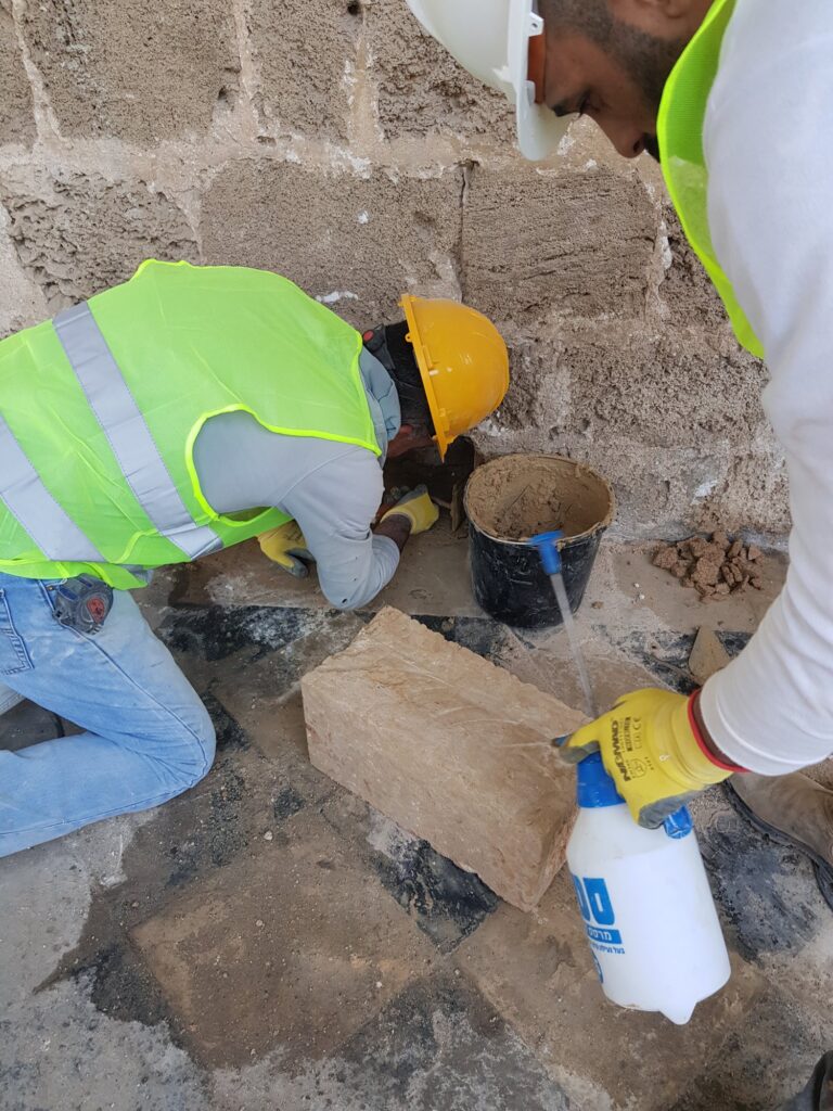 פועלים מרבצים מלט בין אבני הקיר
