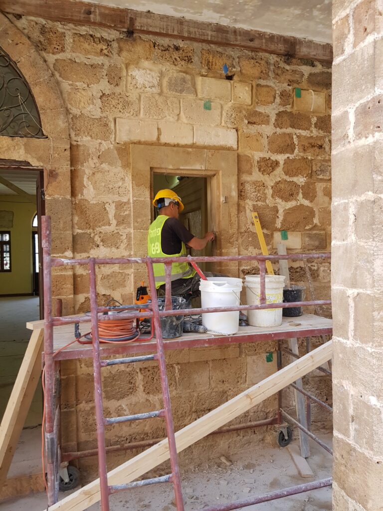 פועל על פיגום מרבץ מלט סביב משקוף חלון