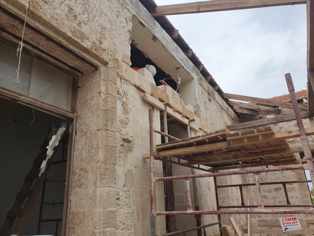 פועלים מתקינים משקוף אבן מעוטר עם רצועות הרמה