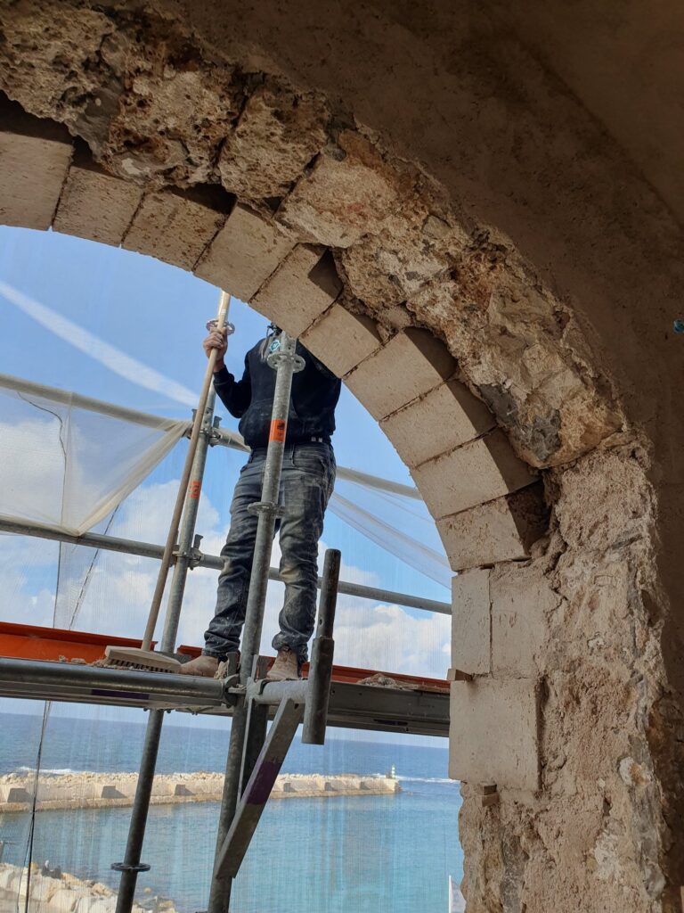פועל בפתח קשתי מול נוף הים