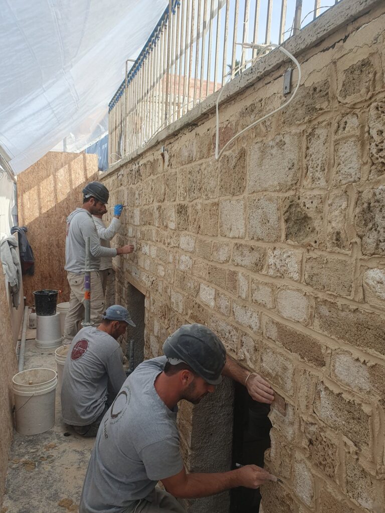 פועל עובד במעבר צר בין קירות אבן
