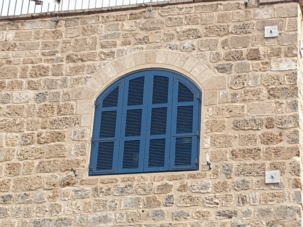חלון קשת כחול משוחזר בקיר כורכר, נמל יפו