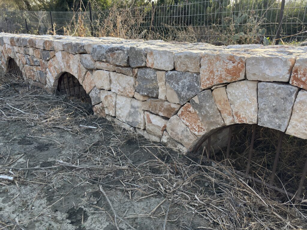 תקריב על שורת קשתות ניקוז קטנות הבנויות בתוך קיר אבן תומך בבנייה יבשה, כרם מהר"ל