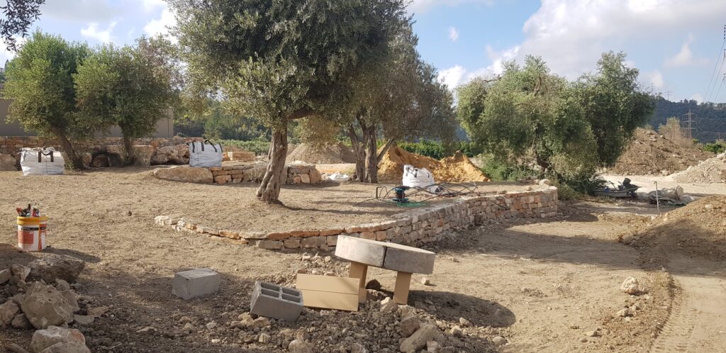 קיר-ספסל אבן נמוך גמור ליד עצי זית