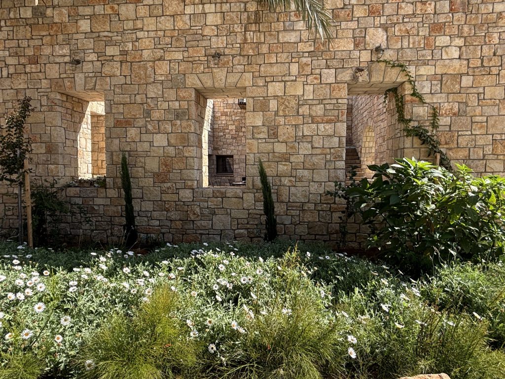קיר אבן עם שלושה פתחים וגינת מרגניות — בית האבן במשמר איילון