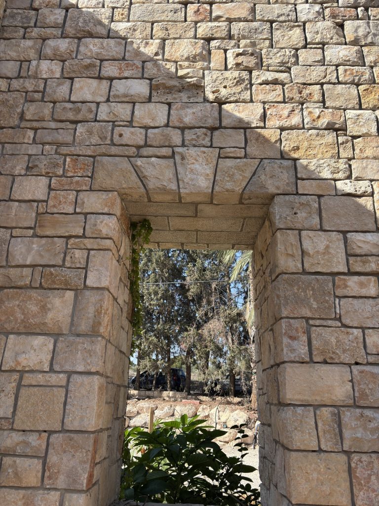 פתח חלון בקיר אבן עבה עם מבט אל העצים — בית האבן במשמר איילון